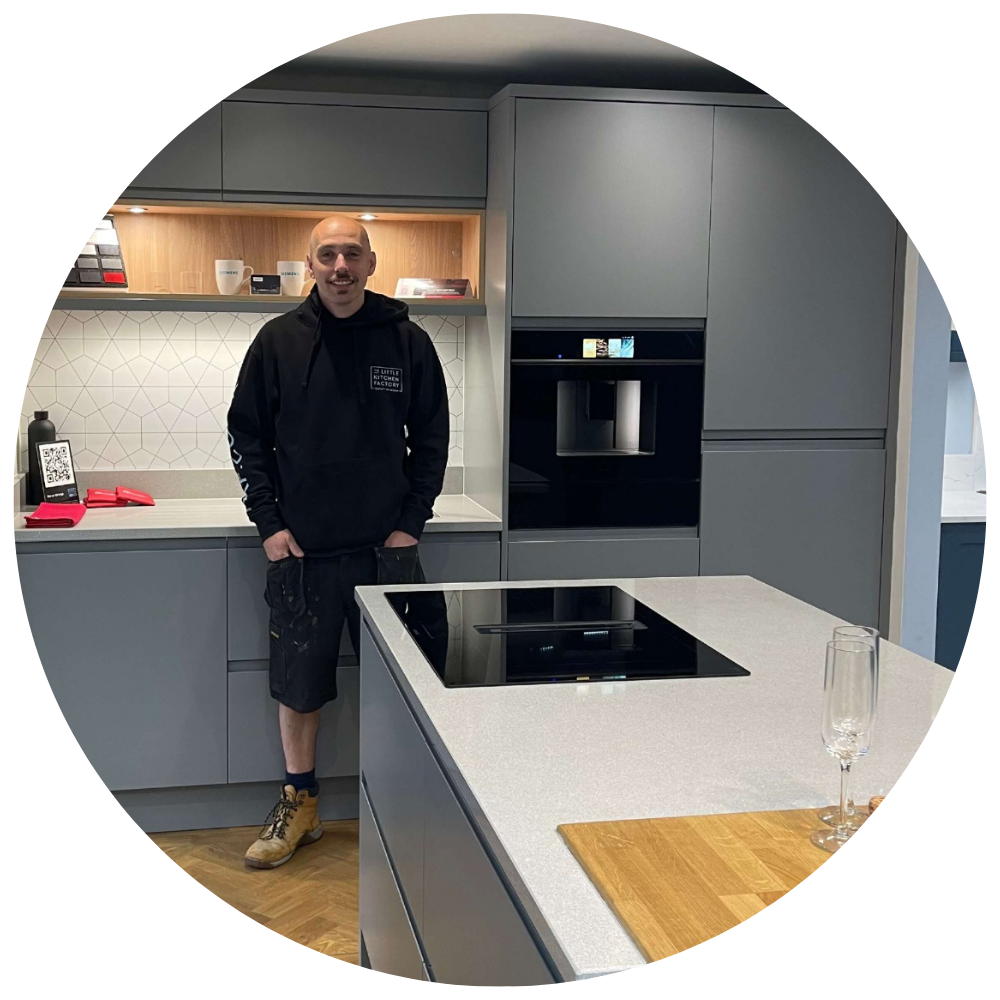 Bryn Smith | The Little Kitchen Factory Team Bryn Smith from The Little Kitchen Factory standing in a grey kitchen showroom