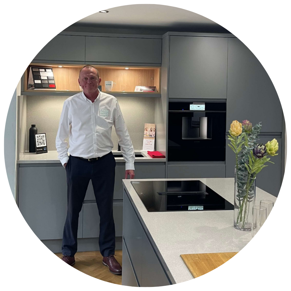 John English | The Little Kitchen Factory Team John English from The Little Kitchen Factory standing in a grey kitchen showroom