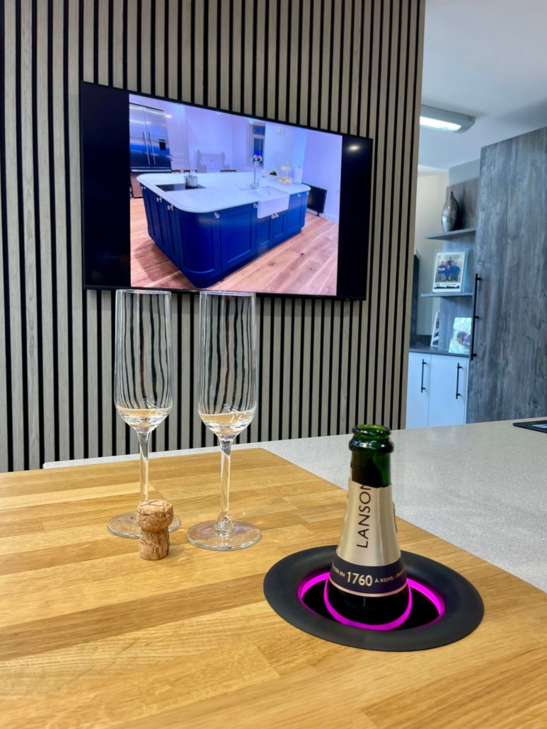 The Little Kitchen Factory showroom with slatted feature wall, wall-mounted TV and kitchen island with integrated bottle chiller