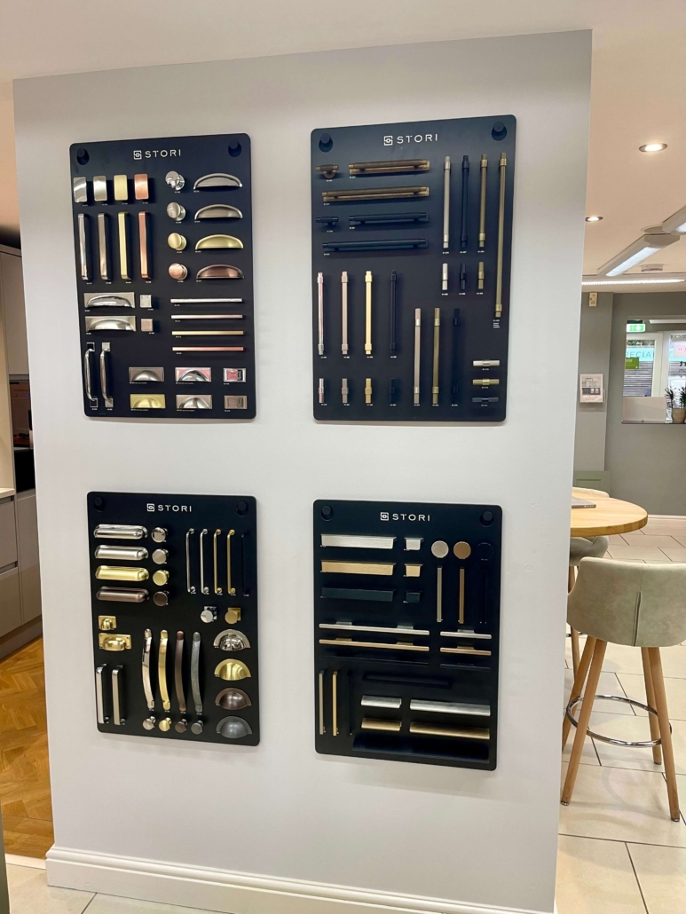 Wall-mounted display of kitchen handles and knobs in various finishes including brass, chrome, and black at The Little Kitchen Factory showroom