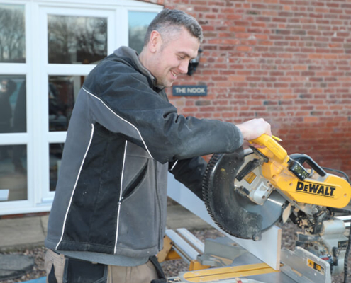 Bespoke FittingBespoke kitchen fitting - fitter using a mitre saw for custom cabinet cutting